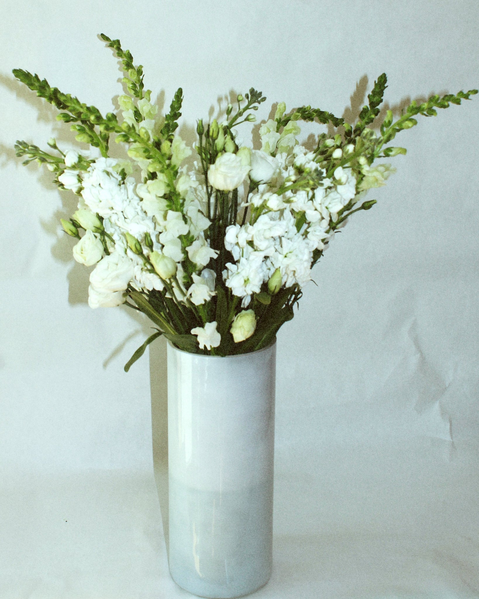 Tall floral arrangement including snapdragon, stock, and lisianthus. 
